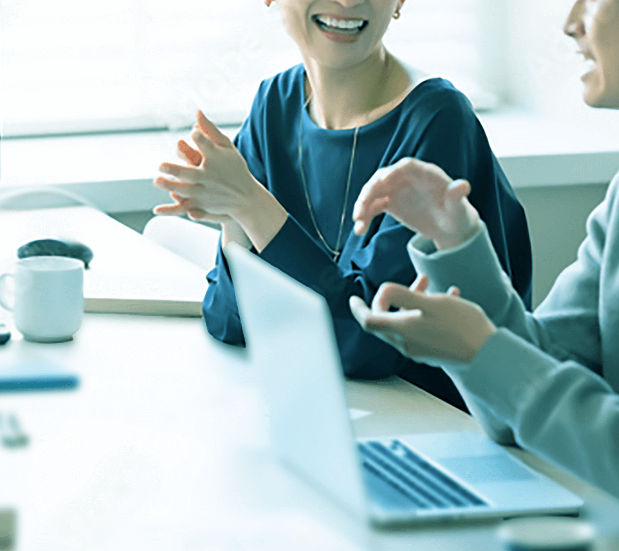 ラップトップを前に笑顔で会話する二人のビジネスパーソンのクローズアップ